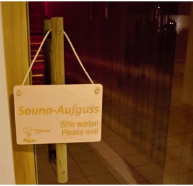 Tafel mit „Sauna-Aufguss, bitte warten!” Anschrift